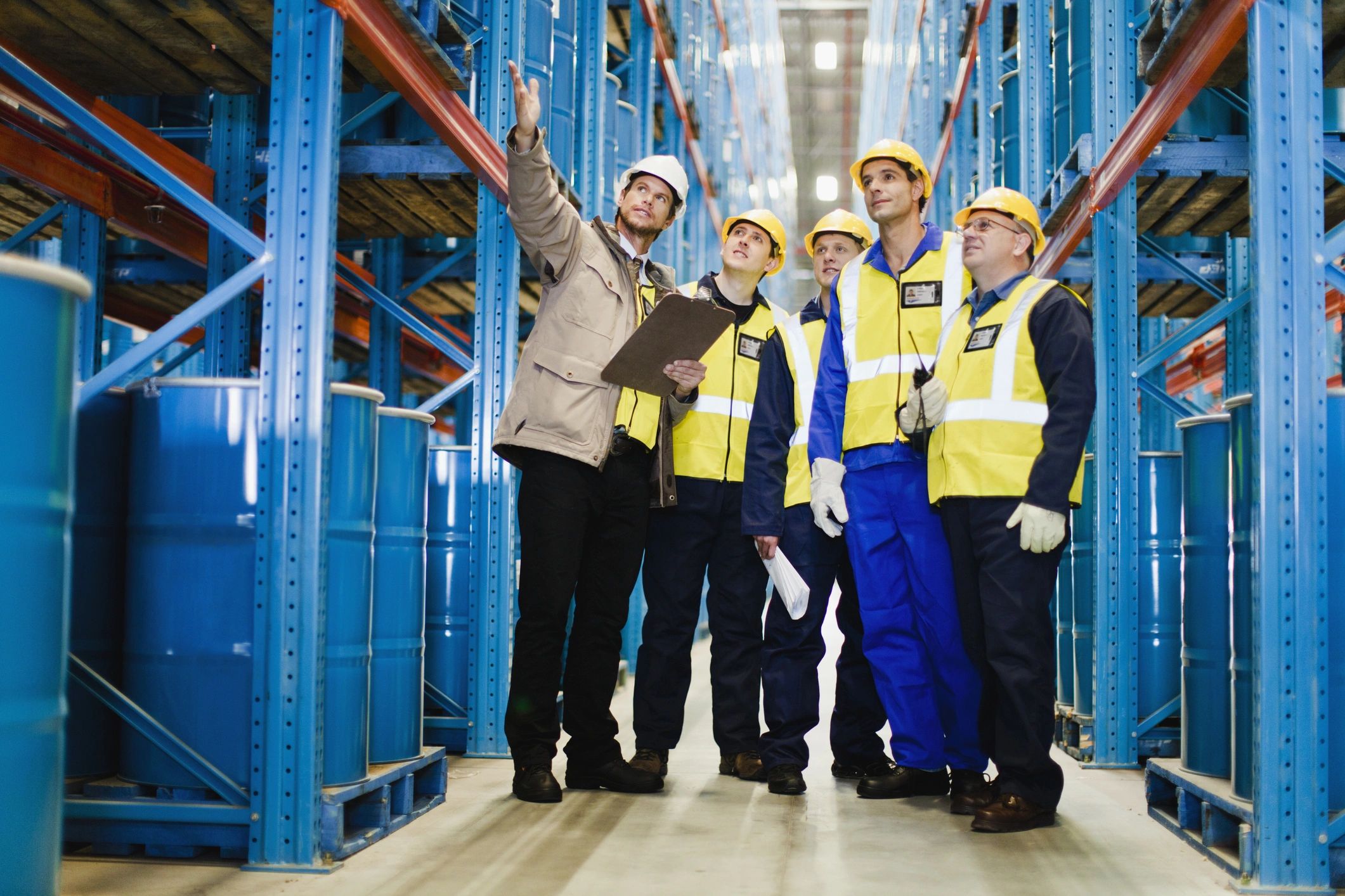 Group of workers in safety gear inspecting warehouse.