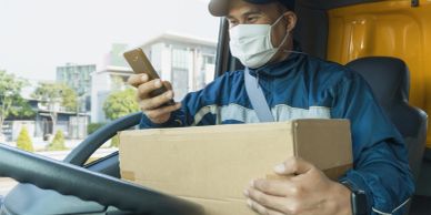 Delivery driver holding a package and phone