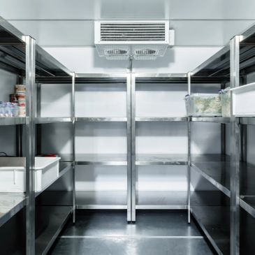 Empty industrial cold storage room with metal shelves.