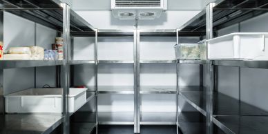 Empty metal shelves inside a refrigerated storage unit.