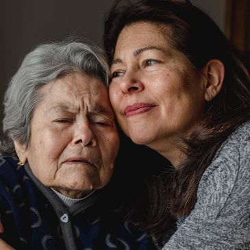 Elderly woman and middle-aged woman sharing a tender moment.