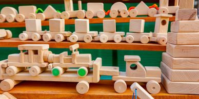Wooden toy vehicles and blocks on shelves.