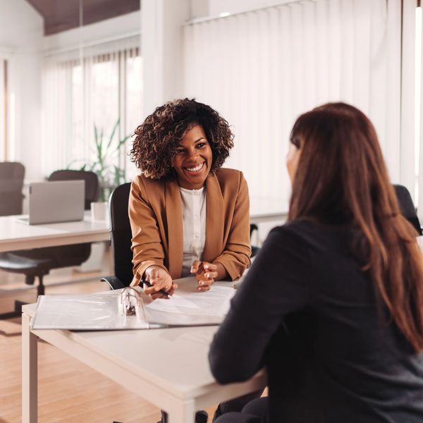 
The image depicts two women in what appears to be an office or meeting room setting. 