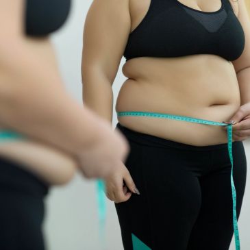 Person measuring waist with tape measure.