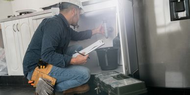 Technician inspecting dishwasher in kitchen.