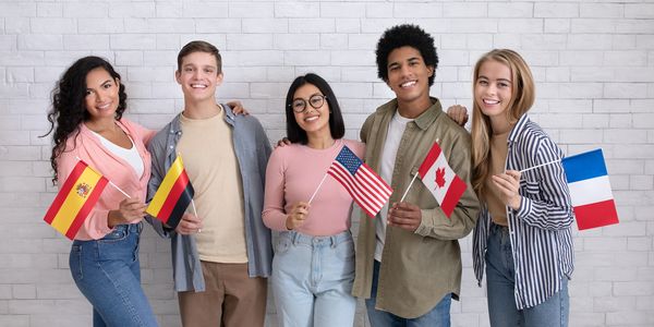 Diverse group of young adults smiling and holding flags from different countries.