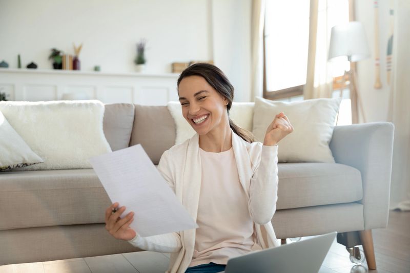 Yes! Overjoyed young woman remote employee reading paper letter from company informing she is hired on vacant place, happy millennial lady bank client getting loan mortgage credit application approval