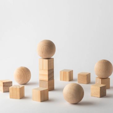 Wooden spheres and cubes arranged on a white surface.