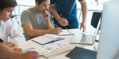 Three people discussing data charts in an office.