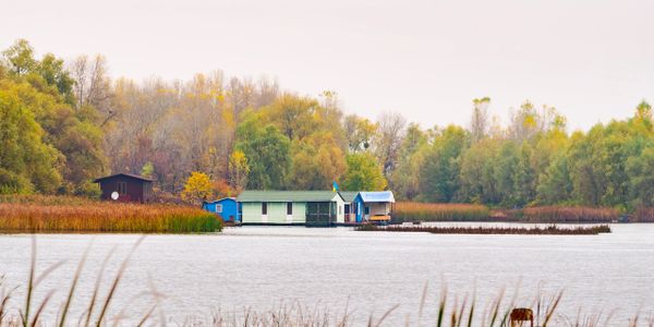 Calm lake with colorful houses and autumn trees in the background.