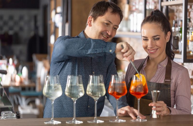 Professional bartender teaches new employee on how to make cocktails.