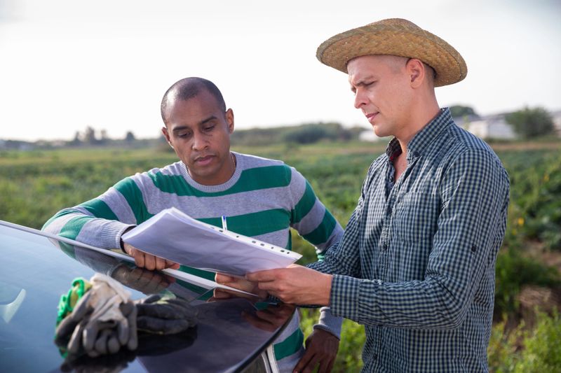 Portrait of two male gardeners signing papers and talking outside