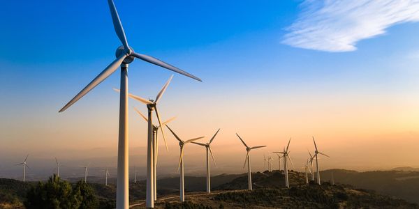 Wind turbines at sunset on a hill.