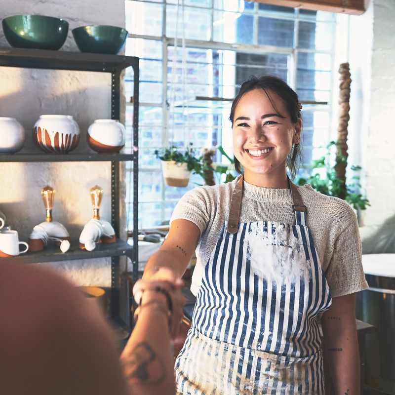 Shot of two young women shaking hands in a pottery studio