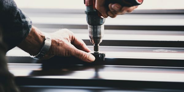 closeup of a mans hands installing metal roofing 