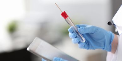 Medical professional holding swab test tube and clipboard.