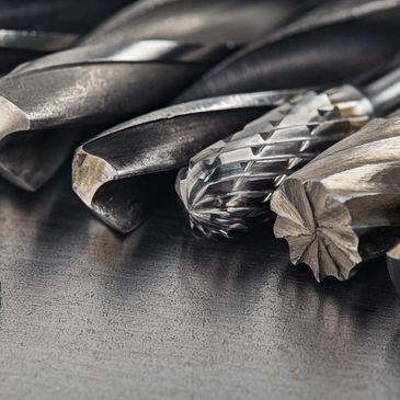 Close-up of metal cutting and shaping tools on a dark surface.