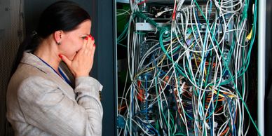 Image of  a woman in a business suit putting her face in her hands as she stares at a rack of gear w