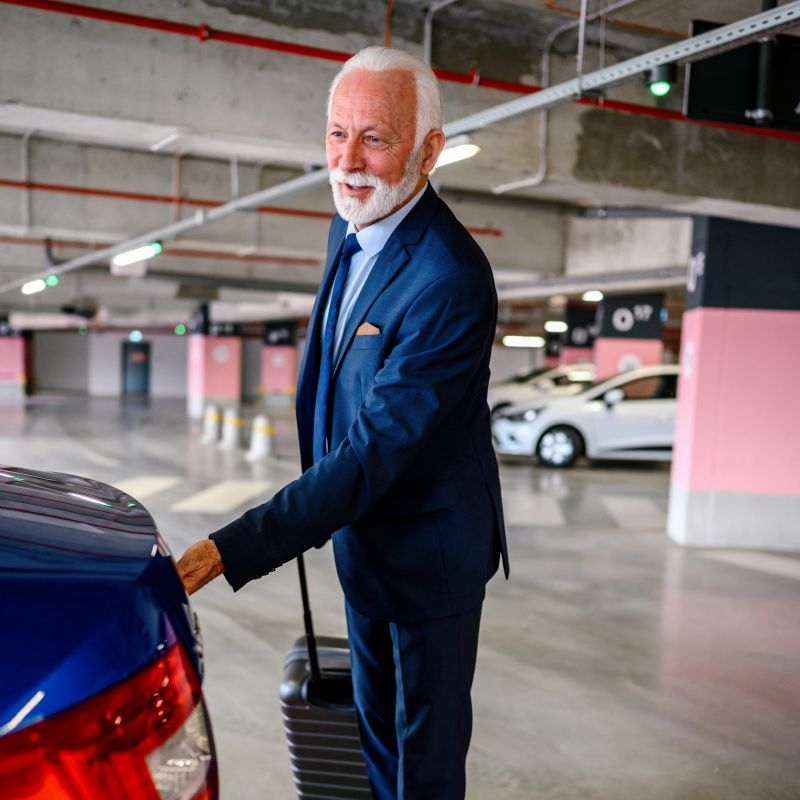 Traveling businessman with his luggage near car.