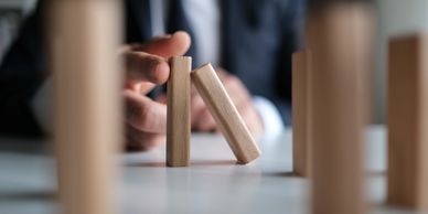 Hand stopping a falling domino piece in a row.