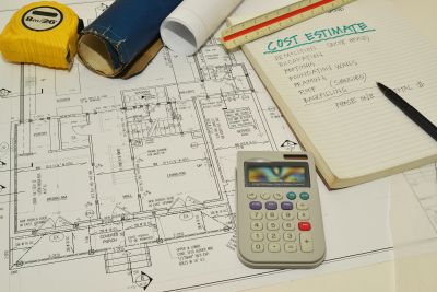 Architectural blueprint with calculator, tape measure, and cost estimate notes.
