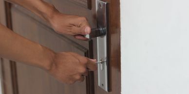 Hands unlocking a door with a key.