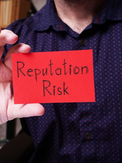 person holding a card that says Reputation Risk
