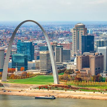 The Gateway Arch in St. Louis with city skyline and river in autumn.