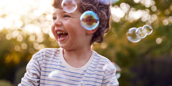 Happy child laughing outdoors with bubbles.