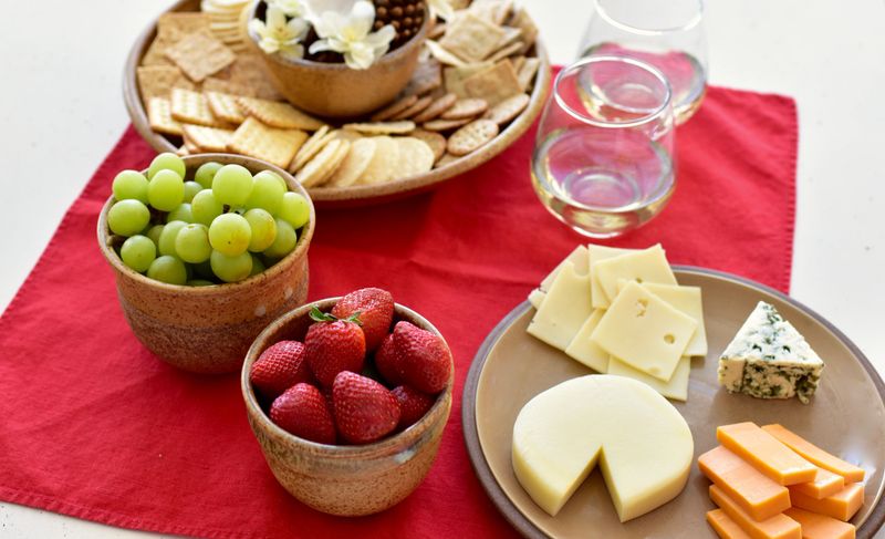 Cheese tray background with poured wine or drinks to share for Valentine's Day, Mother's Day, Christmas, date nights, birthday. Dine in take out. Photo concept, background, food lifestyle, copy space
