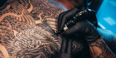 Tattoo artist using a tattoo gun on a person's back