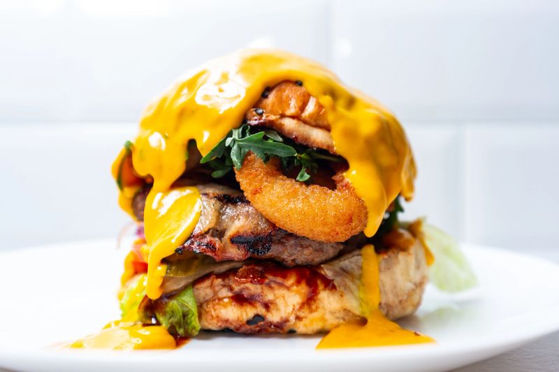 Fresh hamburger covered with melted cheese with grilled beef and onion rings on the plate