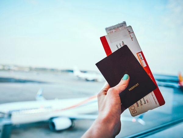 Hand holding a passport and boarding passes at the airport.