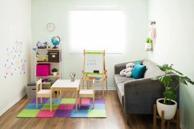 Bright children's playroom with colorful foam mats and small furniture.