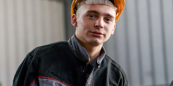 Young male construction worker wearing a helmet and jacket.