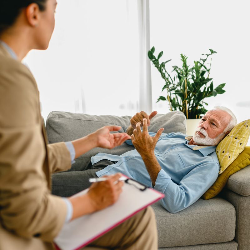 Senior frustrated man solving his mental problems while having a therapy session with psychologist, post covid symptoms.