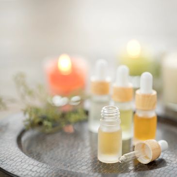 Essential oil bottles with droppers on a textured tray, blurred candles in background.