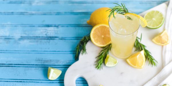 Refreshing lemonade with citrus slices and rosemary on a marble board.