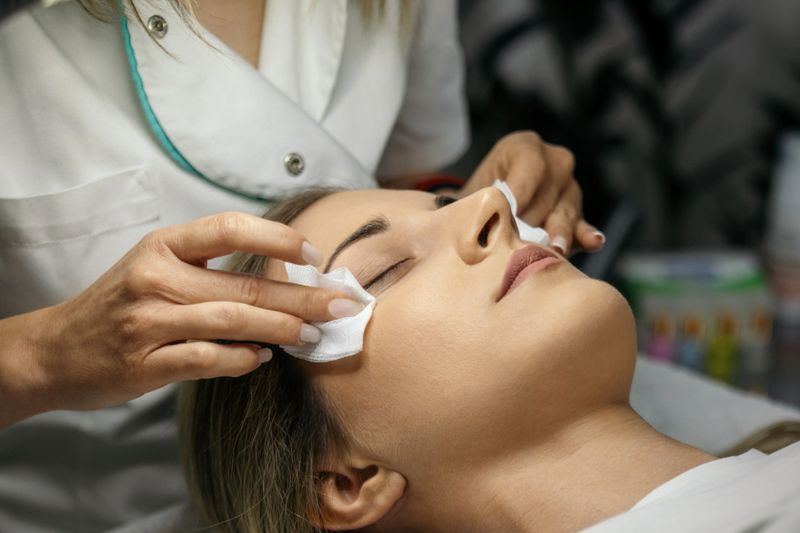 Beautiful young woman with beautiful clean skin having a lash lift treatment. She is laying on the bed, her eyes are closed and the beautician is doing the treatment.