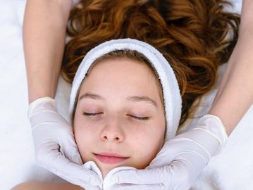 Young woman enjoying a facial treatment with a headband and closed eyes.