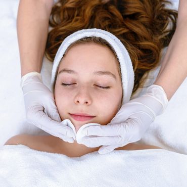 Woman receiving a relaxing facial treatment with eyes closed.