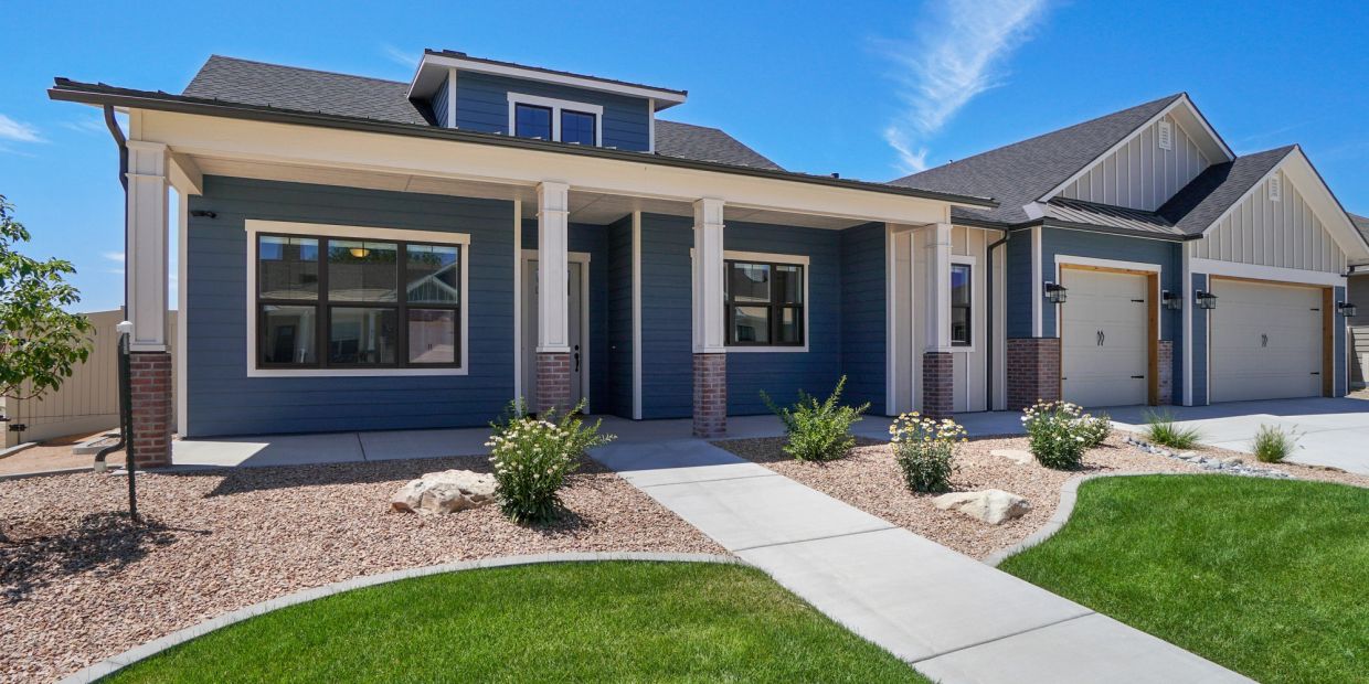 Modern blue house with a spacious front yard and three-car garage.