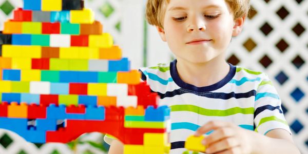 Young boy building colorful structures with toy blocks.