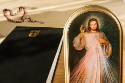 Bible and a framed image of Jesus on a wooden table.