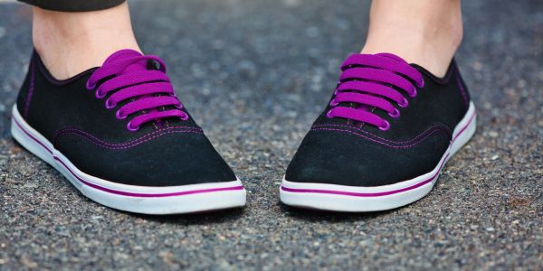 Black shoes with purple laces worn on pavement.