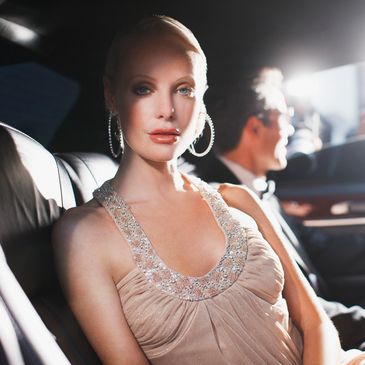 Elegant woman in a car wearing a beige dress.