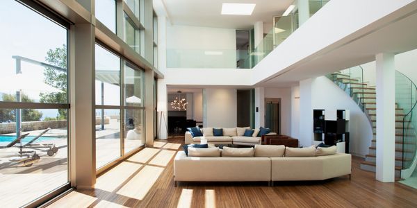 Spacious modern living room with large windows and a curved staircase.