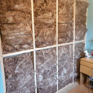 Interior wall insulation installation with exposed fiberglass batts.