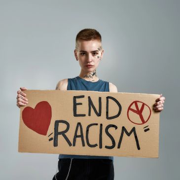 Person holding a sign saying 'End Racism' with a heart and peace symbol.