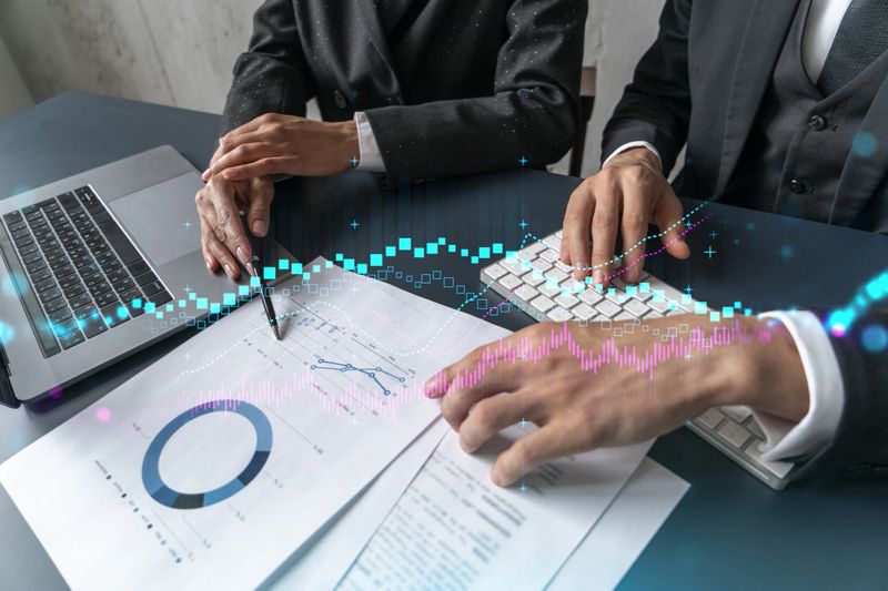 Two business people working together on stock market strategy. Try to analyze forex behavior. Financial graph hologram. Double exposure.